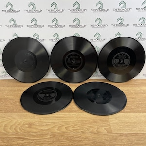 May include: Five circular black Edison phonograph records arranged in a group. Three records are positioned in the back row, and two records are in the front row. Each record features a central label with the Edison brand name and text.