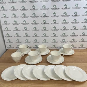 May include: A set of white porcelain dinnerware featuring four teacups with matching saucers and six individual side plates. Each piece displays a subtle, elegant spiral or swirl pattern embossed into the surface, creating a uniform look.