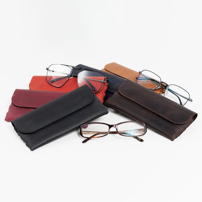 Pode incluir: Uma variedade de &oacute;culos e estojos de couro em v&aacute;rias cores, incluindo preto, vermelho e castanho. Os &oacute;culos t&ecirc;m diferentes estilos de arma&ccedil;&atilde;o, e os estojos s&atilde;o fechados com uma aba.