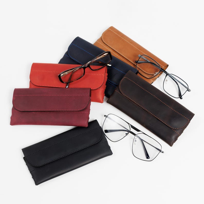 Pode incluir: Uma variedade de &oacute;culos e estojos de couro para &oacute;culos em v&aacute;rias cores, incluindo vermelho, castanho, preto e azul marinho. Os &oacute;culos t&ecirc;m arma&ccedil;&otilde;es pretas e diferentes formatos de lentes. Os estojos s&atilde;o retangulares com fecho de aba.