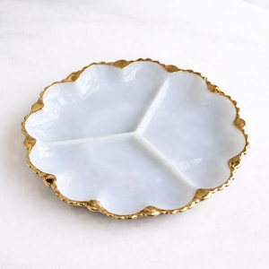 May include: A white, three-section serving dish with a scalloped edge. The rim is trimmed with gold. The dish is designed for serving appetizers, snacks, or small portions of food. The dish is made of ceramic or porcelain.