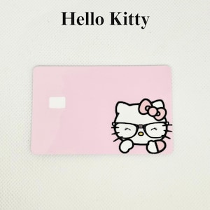 Pu&ograve; includere: Una carta rosa con le parole "Hello Kitty" in alto. La carta presenta una grafica di Hello Kitty con occhiali e un fiocco. La carta ha un quadrato bianco sul lato sinistro.