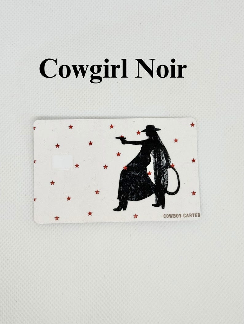 Pu&ograve; includere: Carta rettangolare con sfondo bianco e stelle rosse. Silhouette nera di una cowgirl che tiene una pistola, con il testo "Cowgirl Noir" in alto e "COWBOY CARTER" in basso.