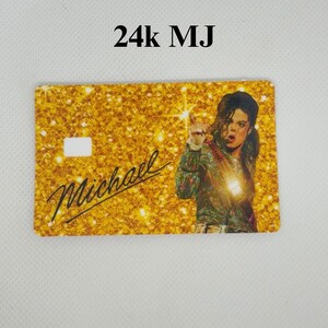 Pu&ograve; includere: Una carta color oro con uno sfondo glitterato e la scritta "24k MJ". La carta presenta una foto di Michael Jackson e il nome "Michael" in corsivo. La carta ha un ritaglio rettangolare bianco.