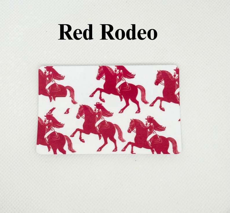 Pu&ograve; includere: Carta rettangolare bianca con un motivo rosso a tema rodeo ripetuto. Il motivo presenta sagome di una persona che cavalca un cavallo. Il testo "Red Rodeo" &egrave; stampato in nero nella parte superiore della carta.