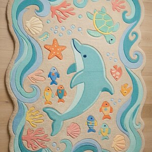 May include: A whimsical, ocean-themed rug featuring a light blue dolphin, colorful fish, a sea turtle, starfish, and coral. The rug has a beige background with blue and teal wave-like borders and accents. The rug is shaped with a scalloped edge.