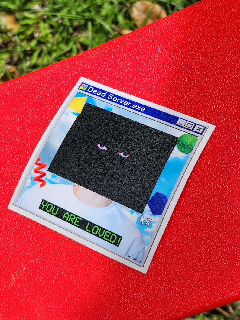 May include: A sticker with a retro computer window design. The top of the sticker reads "Dead Server.exe" in a blue bar. A black square covers the center, with two red eyes visible. The bottom of the sticker reads "YOU ARE LOVED!"
