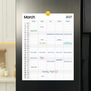 Può includere: Un calendario magnetico bianco per marzo 2027, attaccato a un frigorifero. Il calendario è diviso in colonne giornaliere con spazi per le note. Sono elencate varie attività, tra cui "Yoga @ 9am", "Gym" e "Family Trip!"
