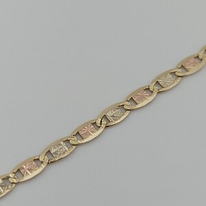 May include: A tri-color gold chain necklace featuring a series of interlocking oval links. Each link is crafted from yellow gold and contains a central square-shaped insert with a textured, diamond-cut finish in alternating rose and white gold.