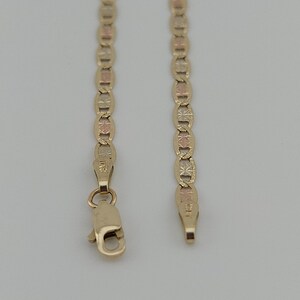 May include: A tri-color gold chain necklace featuring alternating oval links with textured starburst patterns in yellow, rose, and white gold tones. The chain includes a lobster claw clasp and a small metal tag stamped with the number 585.
