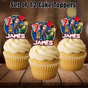 Puede incluir: Tres cupcakes con glaseado blanco, cada uno coronado con un adorno para pastel personalizado. Los adornos presentan un dise&ntilde;o de personaje de dibujos animados con el nombre "JAMES" y el n&uacute;mero "7". El texto "Set of 12 Cake Toppers" est&aacute; en la parte superior.