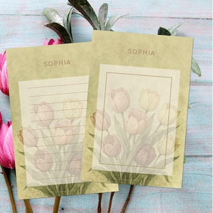 May include: Two stationery sheets with a floral tulip design. The sheets have a light green background with the name "SOPHIA" in a script font. One sheet has lined paper, and the other has a framed floral design. The tulips are in shades of pink and cream.