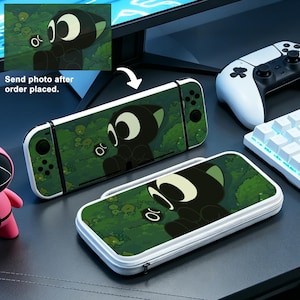 May include: A black and white cartoon character design on a Nintendo Switch console and carrying case. The design is set against a green background with a forest theme. The text "Send photo after order placed" is also visible.