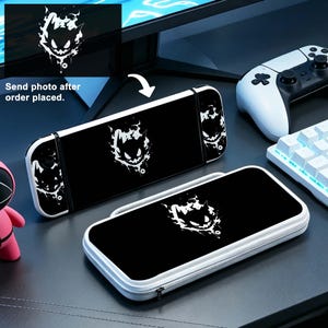 Op de afbeelding: Zwarte en witte Nintendo Switch-hoes en console met een spookontwerp. De hoes heeft een ritssluiting en een witte rand. De console en hoes hebben de tekst "Send photo after order placed."