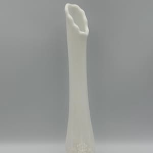 May include: A tall, white vase with a textured surface and a flared, scalloped top. The vase features a decorative embossed grape design near the base. The vase is approximately 12 inches tall, perfect for displaying flowers or as a decorative piece.