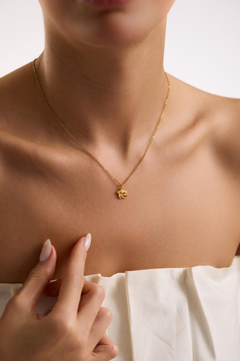 Gold Eye of Horus pendant photographed in soft light, representing ancient Egyptian wisdom and divine protection energy.