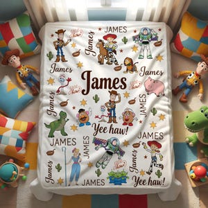 Puede incluir: Una manta blanca con personajes de Toy Story, estrellas y cactus. El nombre "James" se muestra de forma destacada, junto con las frases "Yee haw!" y "Yee chow!". La manta est&aacute; rodeada de coloridas almohadas y juguetes.