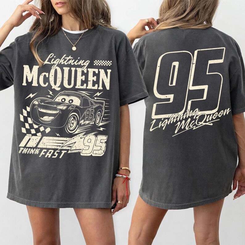 May include: Dark gray t-shirt featuring Lightning McQueen from the Cars movie. The front graphic includes the character, the number 95, and the phrase "Think Fast." The back displays a large "95" and "Lightning McQueen" in a stylized font.