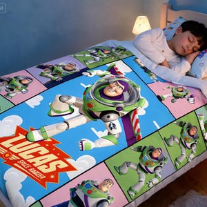 Op de afbeelding: Een kleurrijk sprei met Buzz Lightyear uit Toy Story. Het ontwerp bevat een groot beeld van Buzz in zijn ruimtepak, tegen een blauwe hemelachtergrond met de tekst "LUCAS SPACE RANGER". Het sprei is versierd met meerdere panelen van Buzz Lightyear.