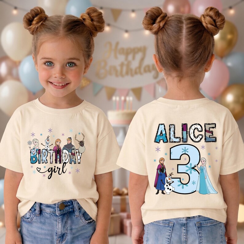 May include: A cream-colored t-shirt featuring a birthday theme. The front displays the text "Birthday Girl" with cartoon characters. The back of the shirt has the name "Alice" and the number "3" with cartoon characters.