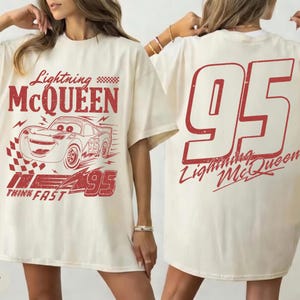 May include: Cream-colored t-shirt featuring a red graphic of Lightning McQueen from the Cars movie. The front design includes the character's image, the number 95, and the text "Lightning McQueen" and "Think Fast." The back displays a large number 95 and the character's name.