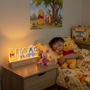 Könnte beinhalten: Ein personalisiertes LED-Namenslicht mit dem Namen LUCAS in Blockbuchstaben, verziert mit Winnie Puuh-Figuren wie Puuh, Ferkel und I-Aah. Die Leuchte ist auf einem rechteckigen Holzsockel montiert und strahlt ein warmes Licht auf den Nachttisch.