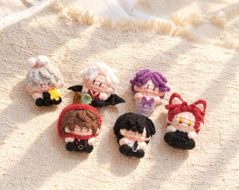 May include: Six small, handcrafted crochet dolls featuring diverse hair colors and outfits, including a grey-haired figure with a yellow star, a white-haired figure with black wings, a purple-haired figure, a brown-hooded figure, a black-haired figure, and a red-eared figure.
