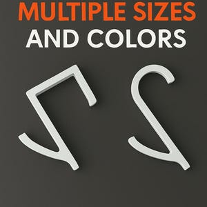 Może przedstawiać: Dwa białe obiekty o abstrakcyjnym kształcie na ciemnoszarym tle. Tekst "AVAILABLE IN MULTIPLE SIZES AND COLORS" jest wyświetlany w kolorze białym i pomarańczowym. Obiekty wydają się być haczykami lub uchwytami.