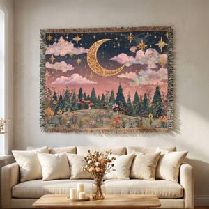 May include: A woven tapestry featuring a night sky with a large crescent moon, stars, and pink clouds above a forest landscape. The scene includes a meadow with colorful flowers and mushrooms, finished with a fringed edge on all four sides.