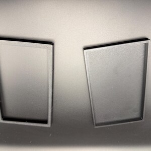 May include: Two black rectangular trays, one with an open frame and the other with a solid base, are displayed against a dark background. The trays appear to be made of a matte material, possibly plastic or a similar substance.