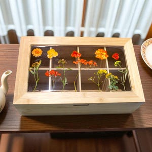 Puede incluir: Una taza de cerámica blanca con un asa negra y el texto "But First, Coffee" en negro, con una fuente de estilo manuscrito. La taza está sobre una superficie blanca.