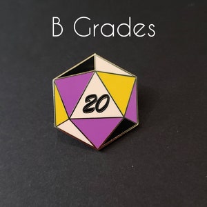 May include: A gold-colored pin shaped like a twenty-sided die with a purple, yellow, and black color scheme. The die has the number "20" written on it in black. The pin is labeled "B Grades".