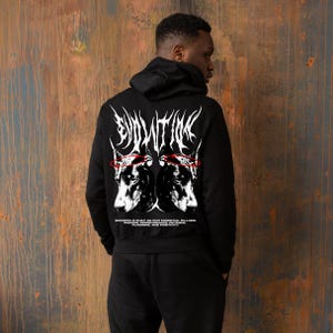 Puede incluir: Sudadera con capucha negra con un diseño gráfico en la espalda. El diseño presenta dos retratos de perros con detalles rojos y la palabra "EVOLUTION" en blanco, junto con texto sobre el éxito. El modelo lleva pantalones negros.