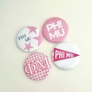 May include: Four round Phi Mu sorority buttons. One button is white with pink stars and the words "PHI MU". Another is pink with the words "PH! MU". A third button is white with a pink pennant and the words "PHI MU". The last button is pink and white checkered with the letters "ΦM".