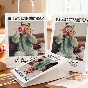 Pu&ograve; includere: Sacchetti regalo di carta bianca con manici, con una foto di una ragazza che tiene delle ciambelle sugli occhi. Il testo "BELLA'S 20TH BIRTHDAY" e "Vintage 2005" sono stampati sui sacchetti. &Egrave; visibile anche un sacchetto pi&ugrave; piccolo con lo stesso design.