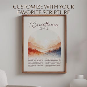 Peut inclure: Tableau encadré avec un paysage à l'aquarelle aux tons orange, rouge et bleu. Le texte "1 Corinthiens 13:4-8" est affiché au-dessus du paysage, avec du texte supplémentaire en dessous. Le cadre est marron chaud.