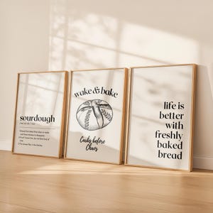 May include: Three framed art prints with a light wood finish. The prints feature text and illustrations related to baking. One print says "sourdough", another says "wake & bake", and the third says "life is better with freshly baked bread".
