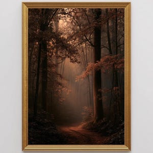 May include: A framed wall art print featuring a forest scene with tall trees and a dirt path. The image displays deep brown and amber tones with light filtering through the canopy, creating a hazy atmosphere. The artwork is encased in a gold frame.