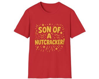 Può includere: T-shirt rossa con la scritta dorata "SON OF A NUTCRACKER!" circondata da stelle e raggi. La maglietta ha girocollo e maniche corte. Un capo festivo.