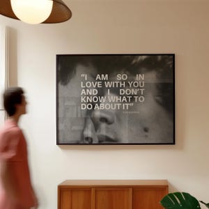 May include: Black framed art print with a grayscale image of a person's face and the quote "I AM SO IN LOVE WITH YOU AND I DON'T KNOW WHAT TO DO ABOUT IT" by Ilya Yakovlev. The print hangs on a white wall.