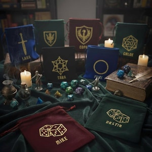 May include: An assortment of velvet dice bags in various colors, each embroidered with unique designs and names. Dice and other tabletop gaming accessories are scattered around the bags, creating a thematic display. The bags are on a dark green velvet surface.