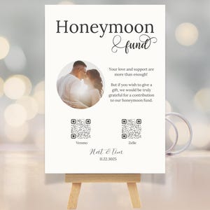 May include: A cream-colored wedding sign with the words "Honeymoon & fund" at the top. It includes a photo of a couple, QR codes for Venmo and Zelle, and the names "Nat & Tim" with the date 11.22.3025.