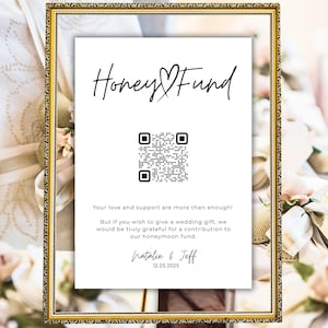 May include: A white card with the text "Honey Fund" in black cursive writing. A black and white QR code is below the text. The text "Your love and support are more than enough! But if you wish to give a wedding gift, we would be truly grateful for a contribution to our honeymoon fund." is below the QR code. The text "Natalie & Jeff" is below the text, and the date "12.23.2025" is below the names.