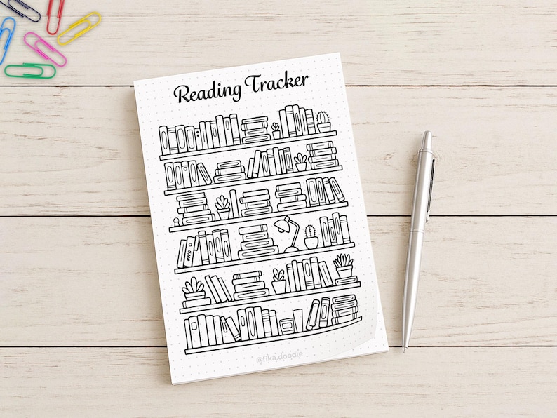 Flat lay photo of a printed reading tracker bookshelf page with pen for bullet journal use