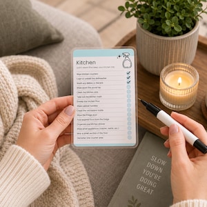 Reusable laminated cleaning card with dry-erase checkmarks and marker. ADHD-friendly room-by-room cleaning checklist helps break household chores into manageable tasks. Printable cleaning cards are editable in Canva, can be laminated and wiped clean, and support simple daily cleaning routines and home organization.