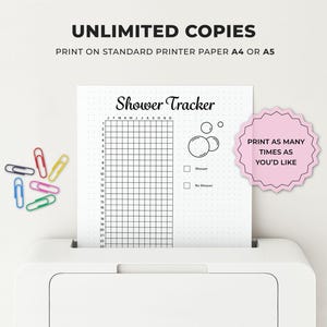 May include: A white printer with a printed "Shower Tracker" sheet. The sheet has a grid, bubbles, and checkboxes. Text on the sheet includes "Shower Tracker" and "J F M A M J J A S O N D". Colorful paper clips are scattered around the printer.