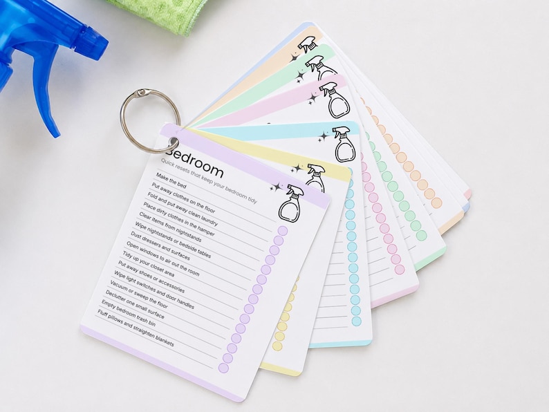 Laminated cleaning cards displayed on a binder ring for easy access and organization. Reusable room-by-room cleaning checklist cards designed for ADHD-friendly cleaning routines. Printable Canva editable cleaning cards can be laminated, checked off, wiped clean, and reused for household chores and home organization.