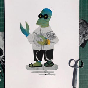 May include: A mixed-media artwork featuring a humanoid alien figure with a blue and green textured head and claw-like hand. The figure wears a white shirt, black pants, and sandals. The artwork is on white paper with scissors and other cutouts nearby.