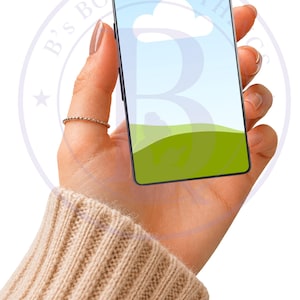Può includere: Uno smartphone che mostra una scena paesaggistica con cielo blu, nuvola bianca e colline verdi. Il telefono è tenuto in una mano con un anello e un maglione beige. Il testo "AI generated" è nell'angolo in basso a destra.