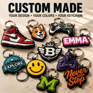 Può includere: Una collezione di portachiavi in gomma personalizzati con vari design, tra cui una sneaker rossa e bianca, un muso di corgi, un controller di gioco, il nome EMMA, una lettera B con ali, una scena di montagna con il testo EXPLORE, una faccina sorridente, una lettera M, una figura incappucciata viola e il testo NEVER STOP.